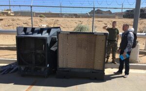 Servicepeople standing near Portacool evaporative coolers to protect them from heat.