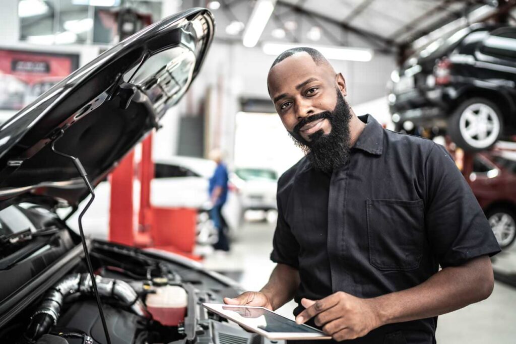 Mechanic smiles while learning how to choose a garage fan, standing in his garage.