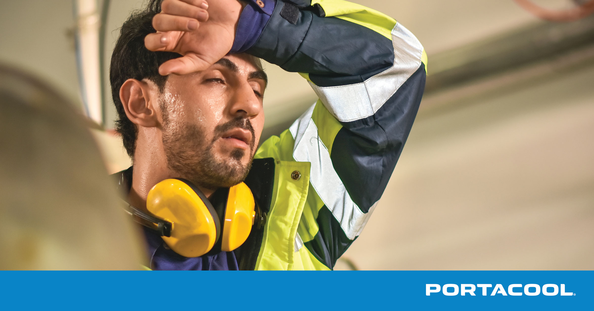 An industrial worker stops to wipe his brow in the heat.