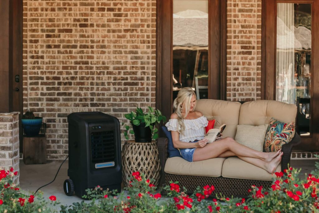 Woman sits near an evaporative cooler wondering why is it called a swamp cooler