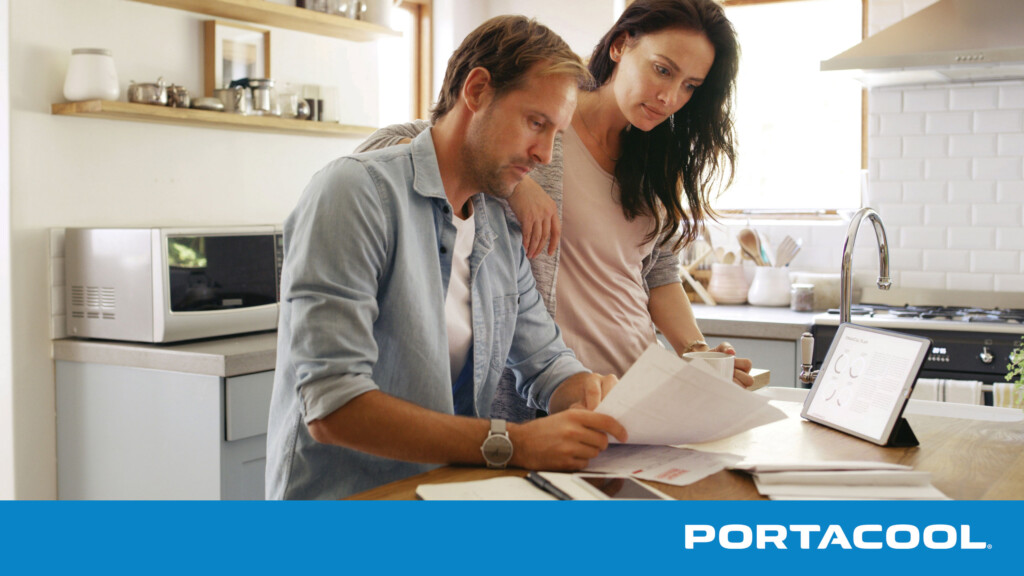 A couple looks with concern at their utility bills related to air conditioning usage.