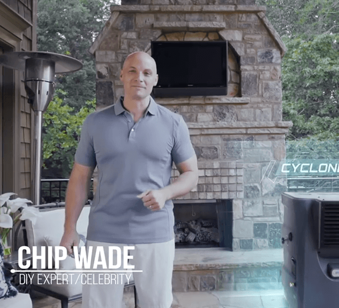 A person stands by an outdoor fireplace, wearing a blue polo and white shorts. Text: "Chip Wade, DIY Expert/Celebrity" and "Cyclone 130." A portable cooler is nearby.