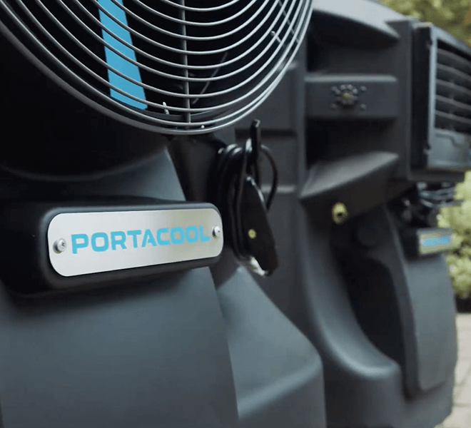 Close-up of black Cyclone with blue logo, showcasing large fan and controls. Fan grill contrasts with greenery, ideal for outdoor demo.
