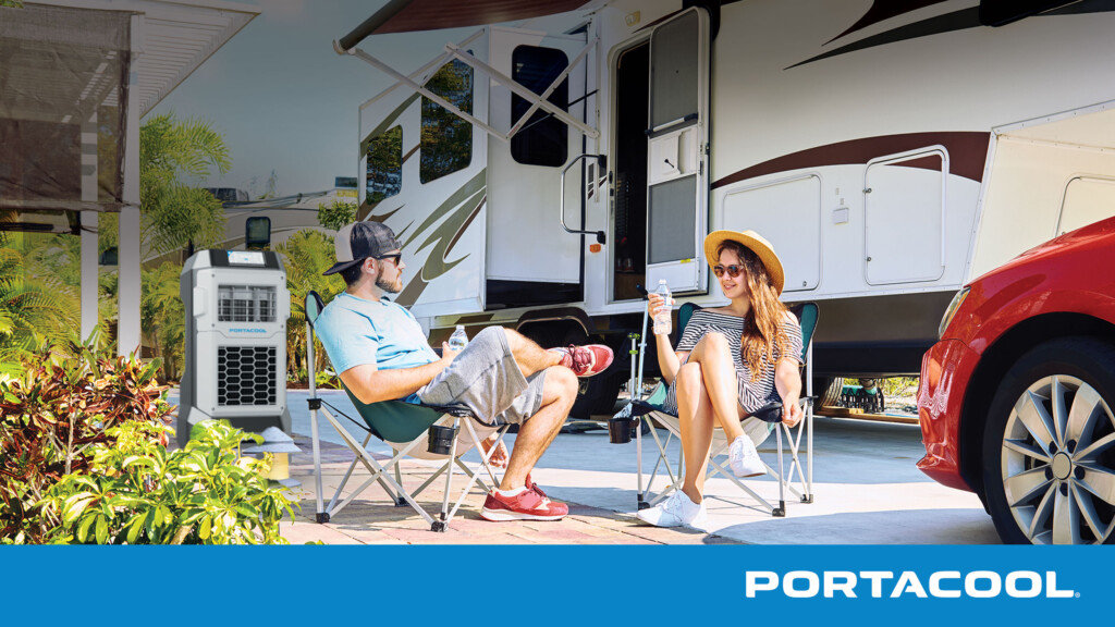 A couple sits outside their RV, enjoying the sun while being cooled by a Portacool evap cooler.