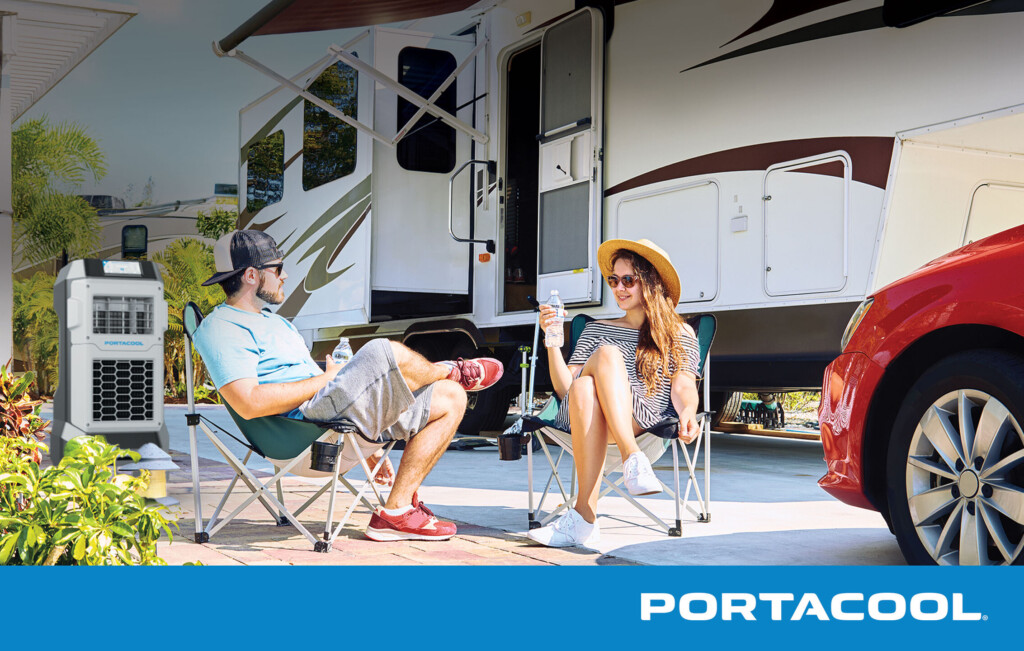 A couple sits outside their RV, enjoying the sun while being cooled by a Portacool evap cooler.
