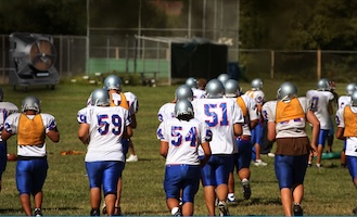 Football team runs onto the field with a Portacool evaporative cooler in the background.