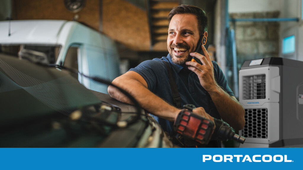 A car mechanic talks on the phone in an automotive service shop, with a Portacool evaporative cooler running in the background.