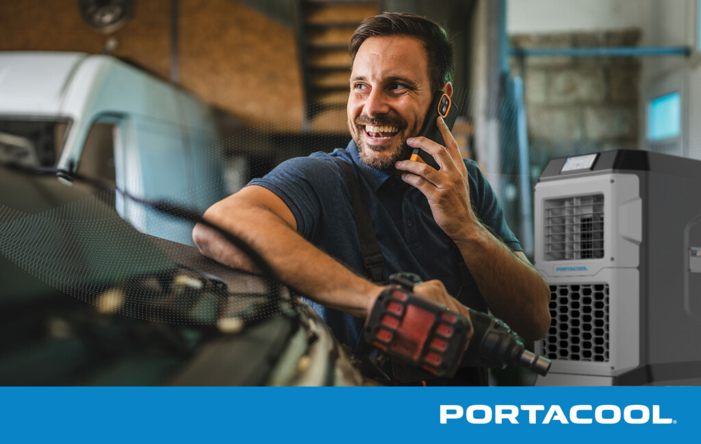 A car mechanic talks on the phone in an automotive service shop, with a Portacool evaporative cooler running in the background.