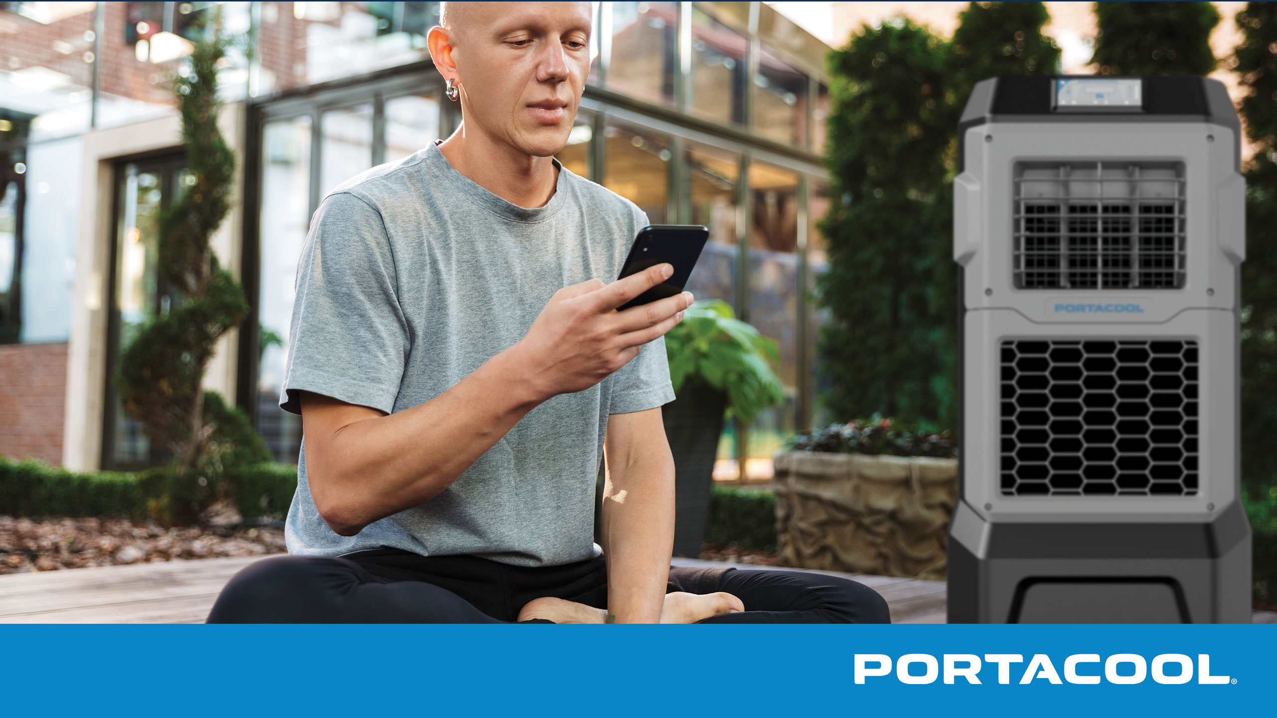 A person sitting on their patio adjusts the controls on their Portacool evaporative cooler from their smartphone using the Portacool CoolSync app.