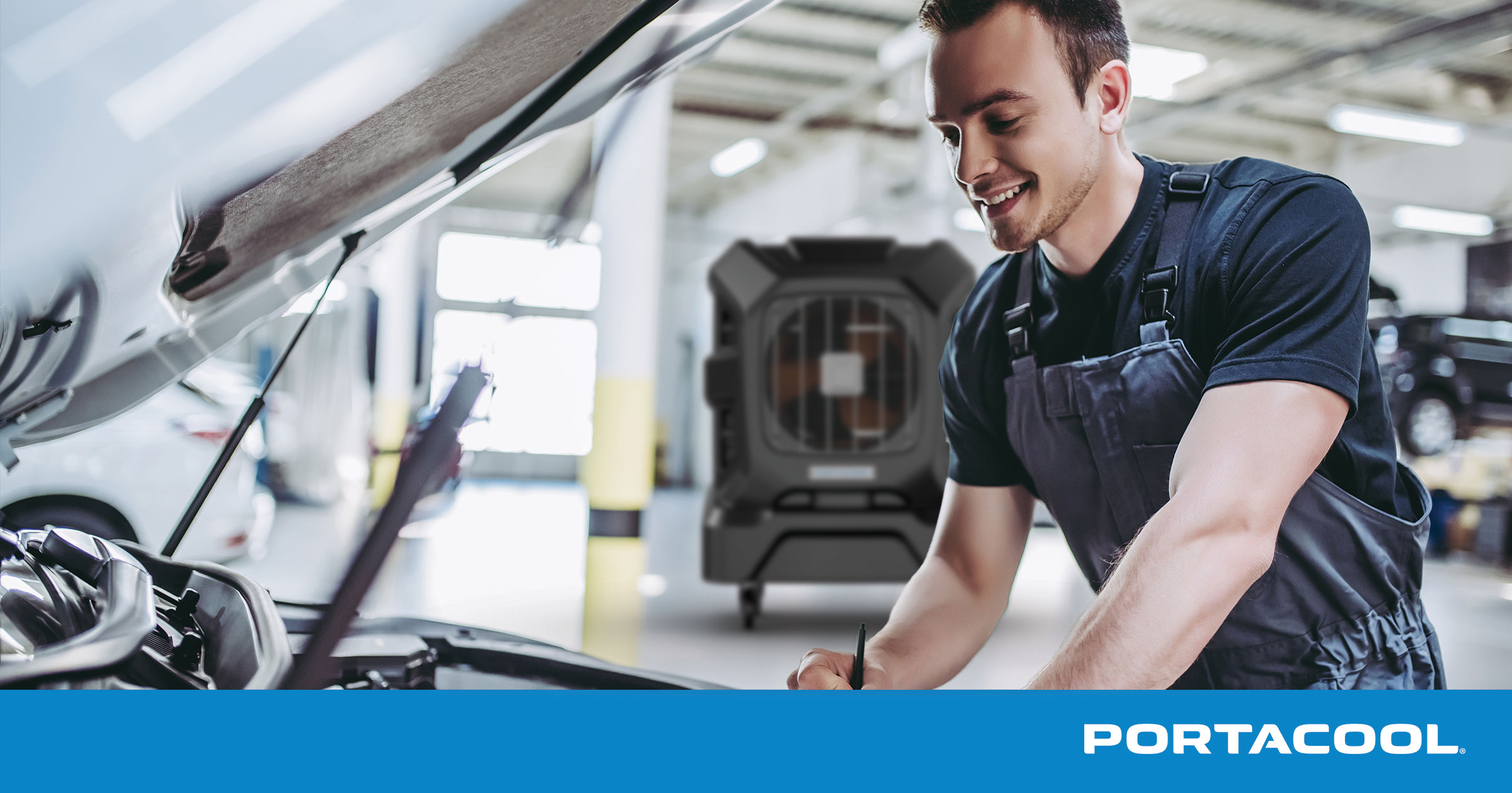 An auto shop technician works in a car's engine bay while being kept cool by a Portacool evaporative cooler.