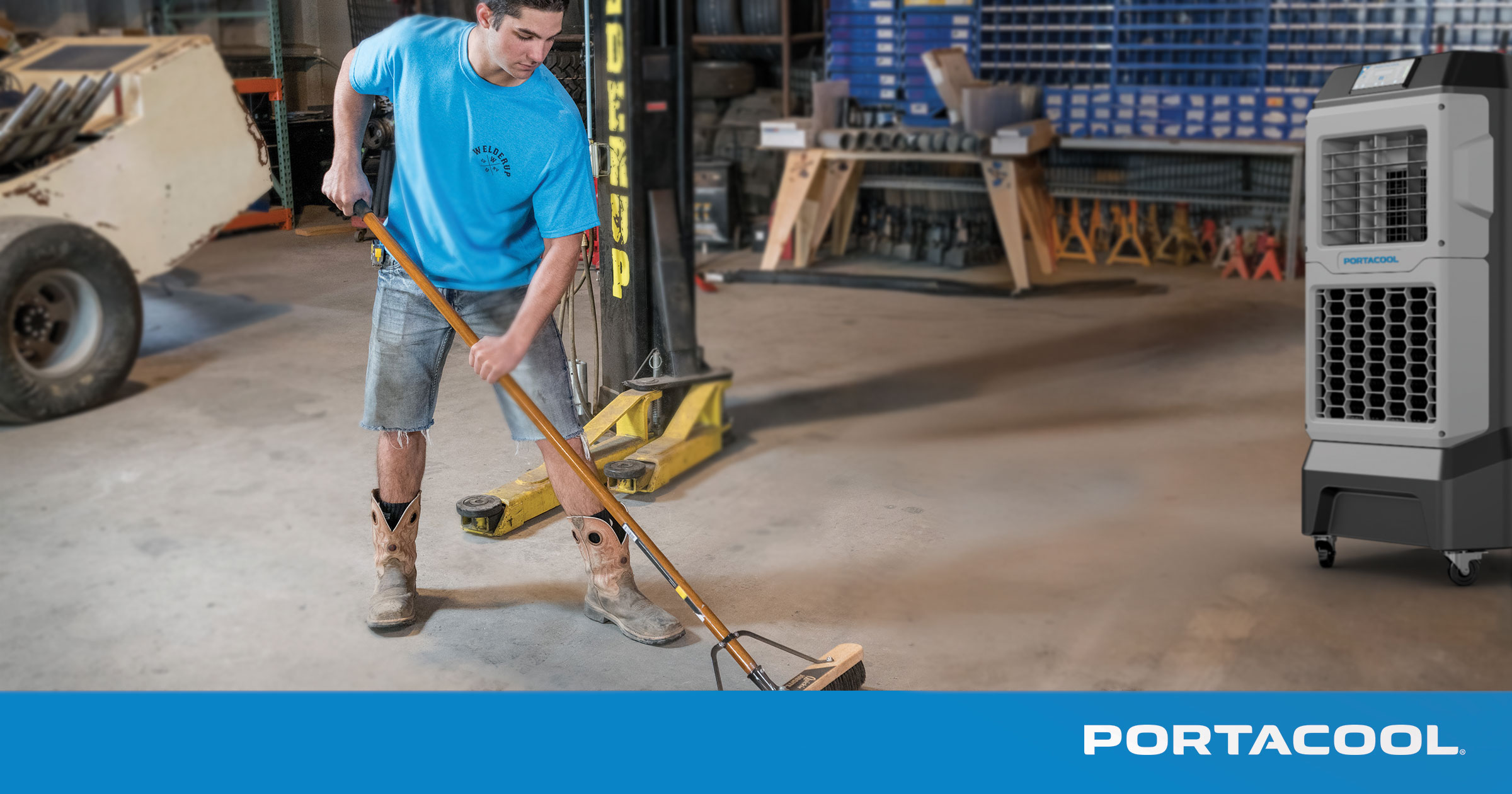 An auto shop technician cleans the shop floor while being kept cool by a Portacool evaporative cooler.