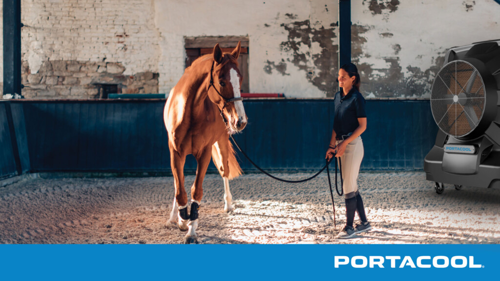 An equestrian trainer works with a horse while being kept comfortable and cool by a Portacool evap cooler.
